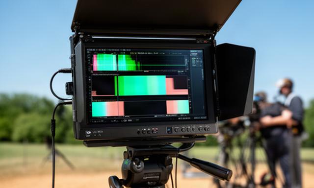 Field monitor da 7 pollici ad alta luminosità su treppiede in un esterno assolato con waveform visibile