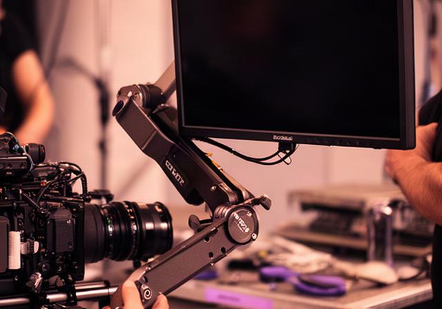 Braccio articolato con monitor esterno fissato su una cage durante una preparazione sul set